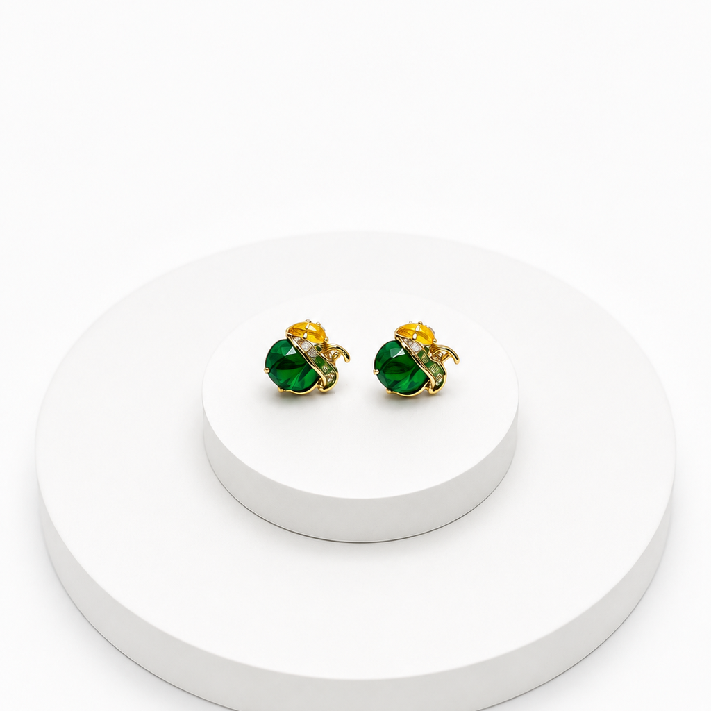 A pair of gold and green stud earrings displayed on a white tiered pedestal against a clean white background.