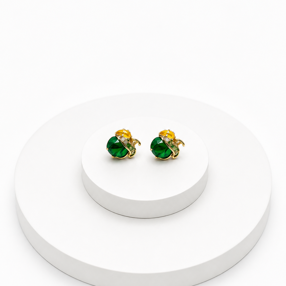 A pair of gold and green stud earrings displayed on a white tiered pedestal against a clean white background.