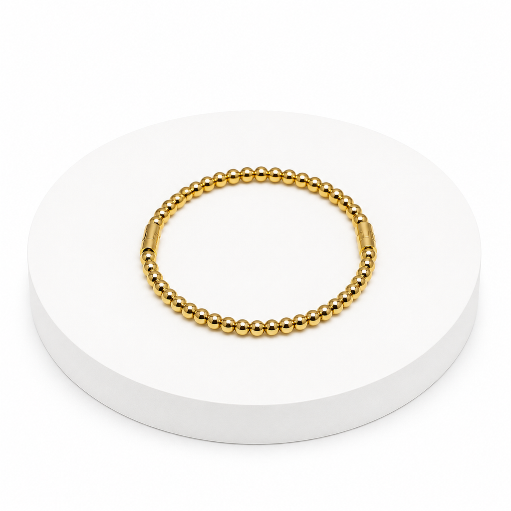 Gold beaded bracelet on a white circular stand with a white background