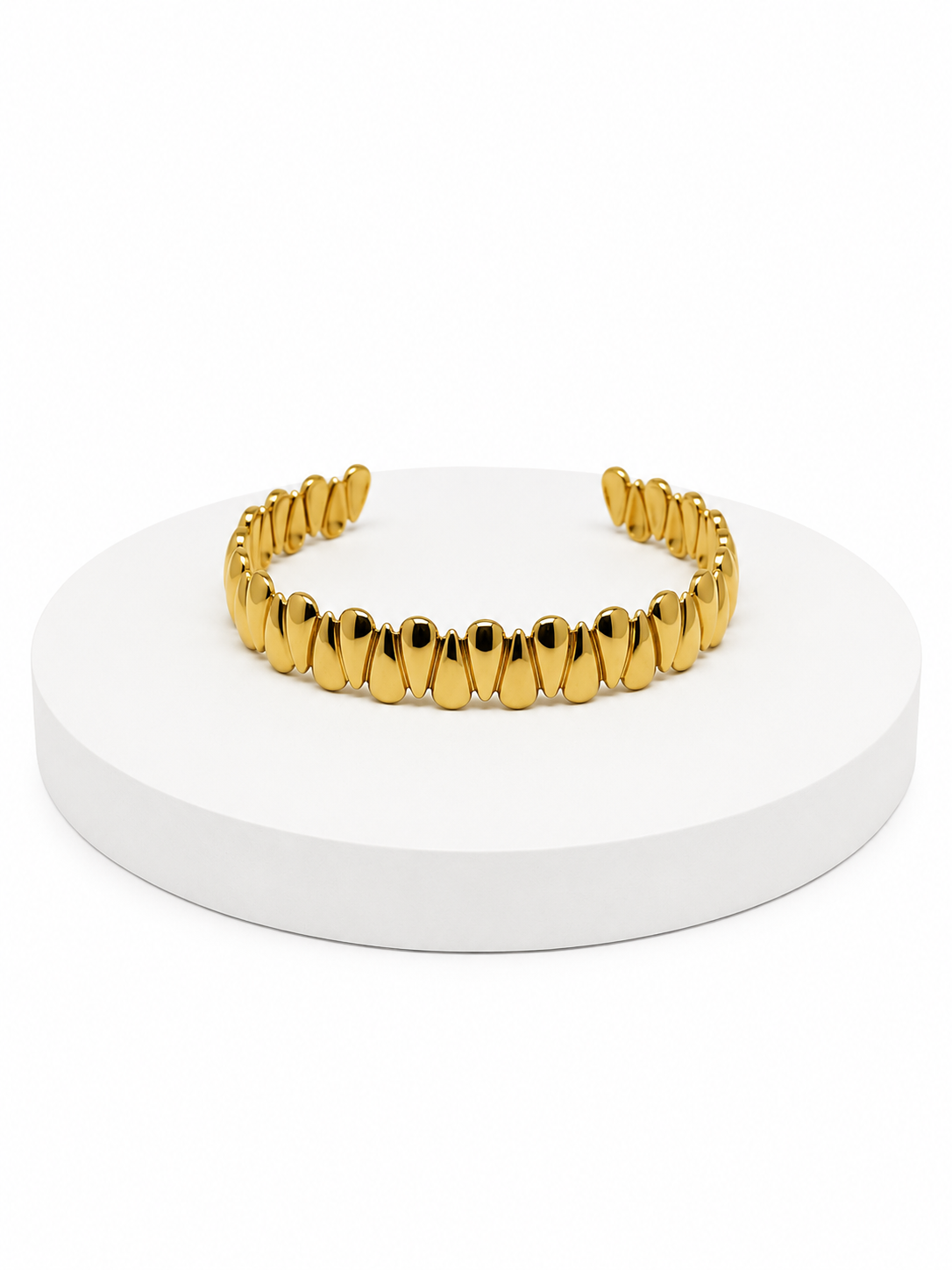Gold bracelet on a white round stand with a white background