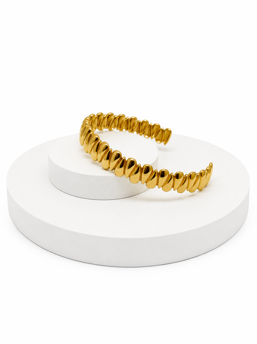 Gold bracelet on a white stand with a white background