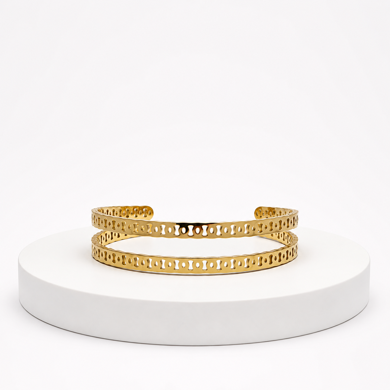 Gold bracelet on a white pedestal with a white background