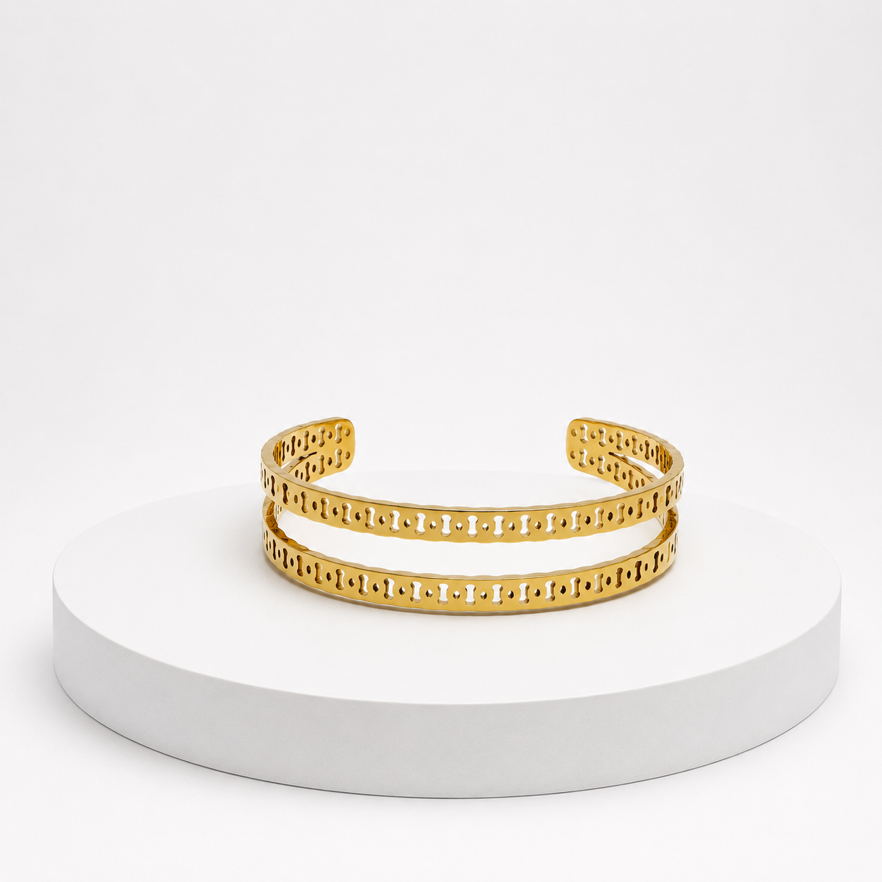 Gold bracelet on a white pedestal with a white background