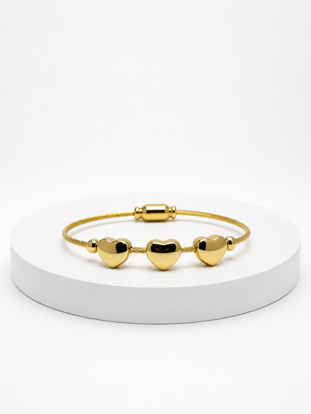 Gold bracelet with heart-shaped charms on a white platform