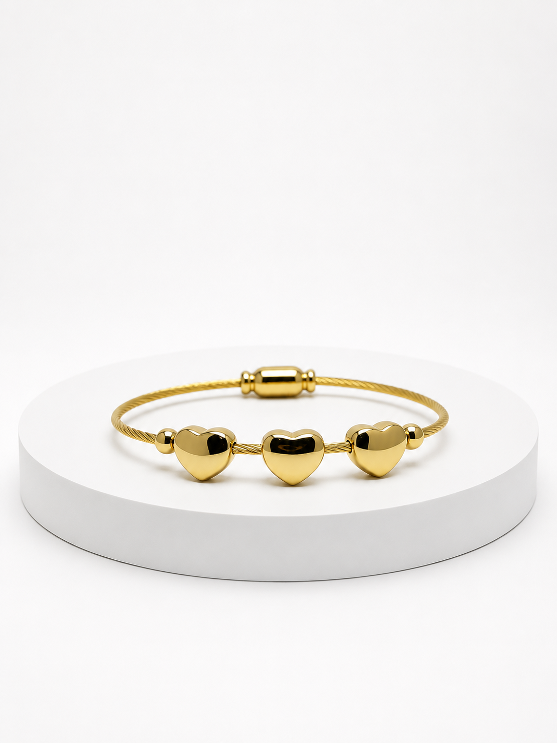 Gold bracelet with heart-shaped charms on a white platform