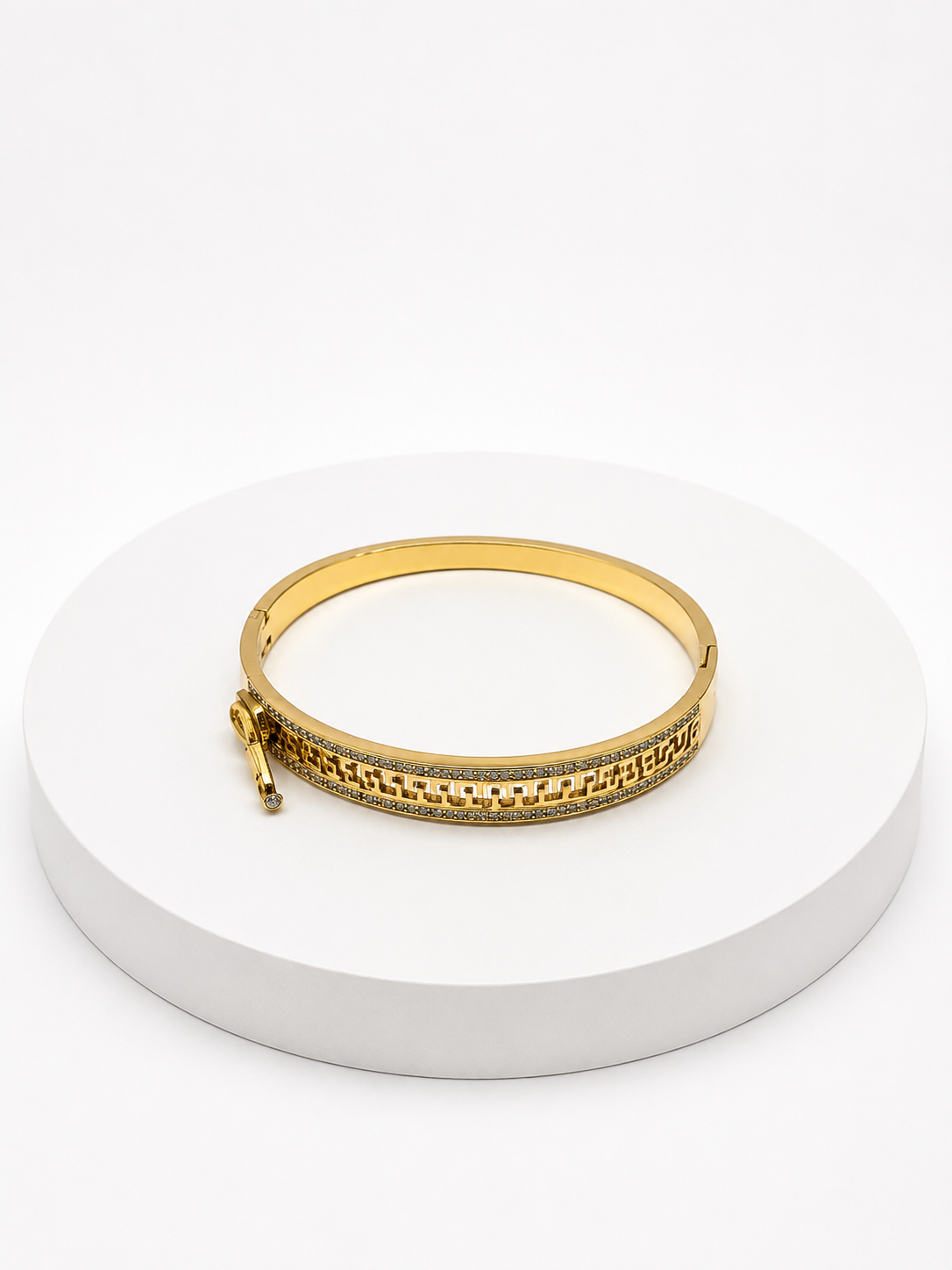 Gold bracelet on a white circular stand with a white background